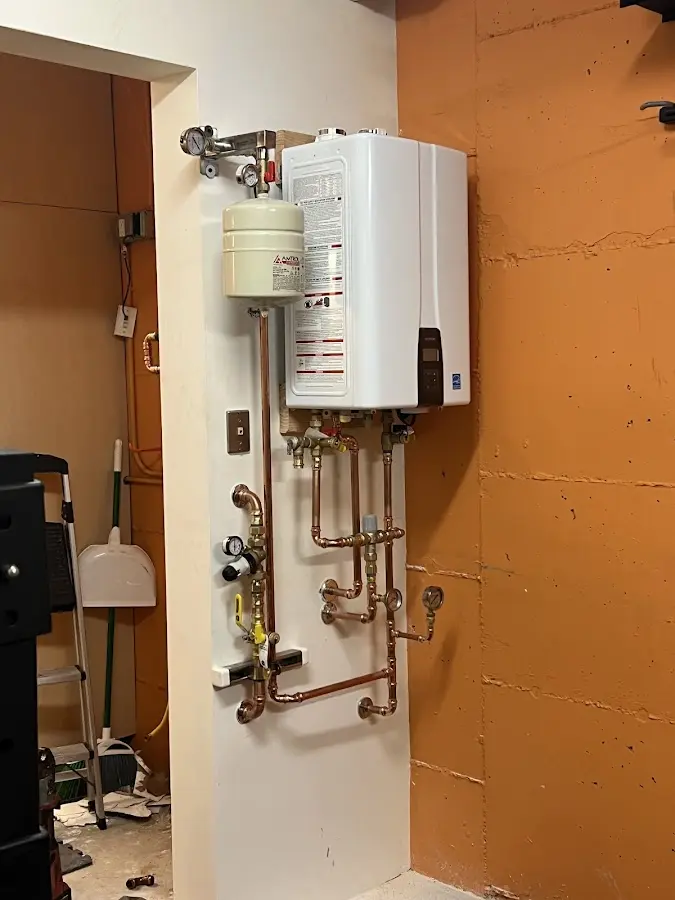 Plumbing technician inspecting water heater connections in Grantville
